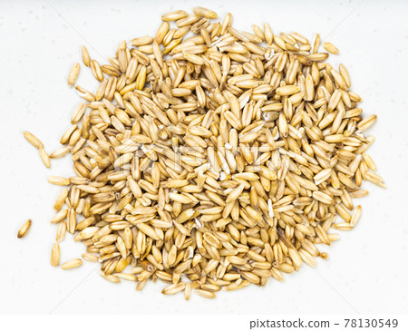 pile of unpolished oat grains close up on gray 78130549