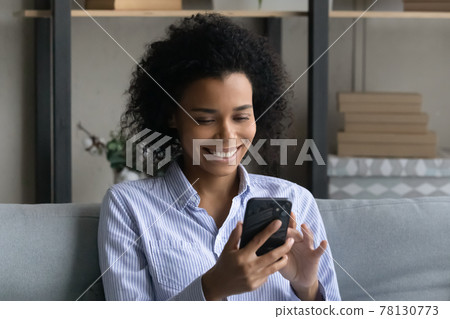 Smiling African American woman use smartphone at home Smiling African American woman use smartphone at home 78130773