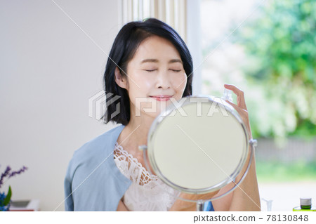 Middle-aged woman doing skin care in the living room 78130848