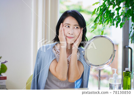 Middle-aged woman doing skin care in the living room 78130850