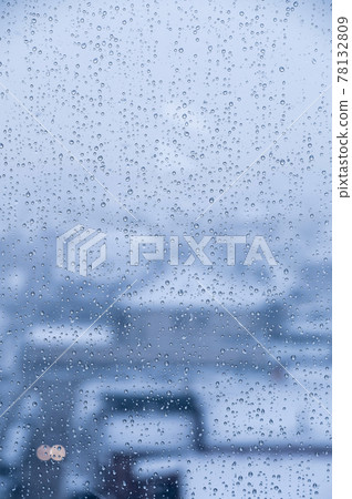 Water droplets on glass in rainy weather with small town sleeping areas out of focus in the background. Autumn cold wet background 78132809