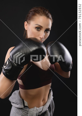 Portrait Caucasian fitness girl in boxing gloves stands in a rack on a black background, portrait of a strong and independent woman fighter Portrait Caucasian fitness girl in boxing gloves stands in a rack on a black background, portrait of a strong and independent woman fighter 78132832