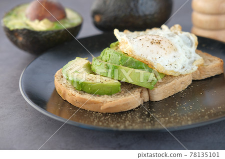Avocado, brown bread, egg and rosemary on table 78135101