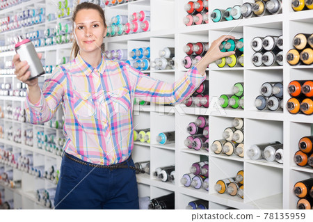 portrait of woman choosing paint color in aerosol can in art shop 78135959
