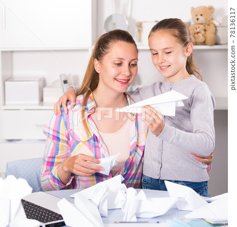 Woman and girl making airplanes of pape Woman and girl making airplanes of pape 78136117