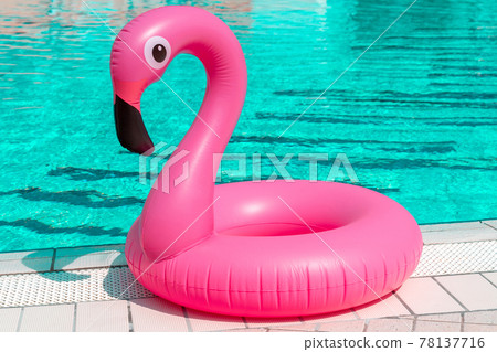 Summer time. Pink inflatable flamingo in pool water for summer beach background. Funny bird toy for kids. 78137716