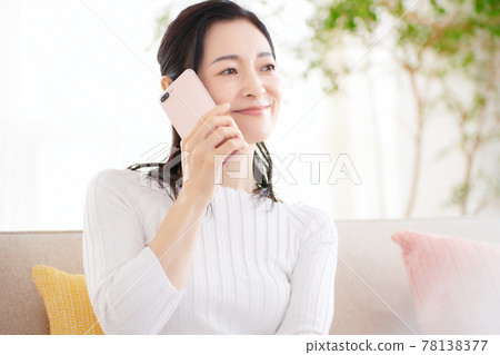 看著智能手機在客廳裡的中年女人 看著智能手機在客廳裡的中年女人 78138377
