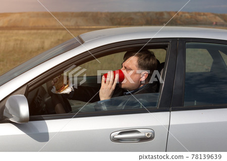 The manager eats lunch at the wheel in the car 78139639