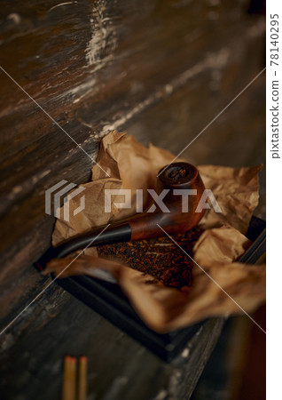 Smoking pipe and a pile of tobacco on wooden table Smoking pipe and a pile of tobacco on wooden table 78140295