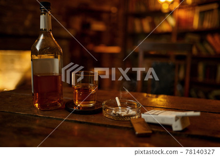 Cigarette in ashtray and alcohol on wooden table 78140327