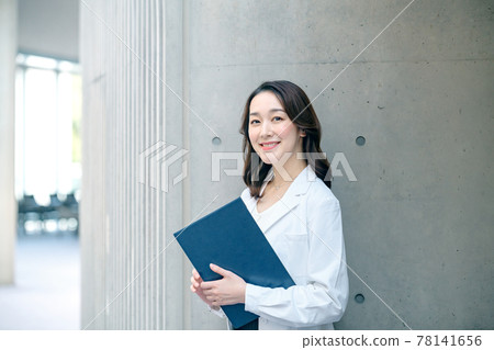 Female doctor with a smiling clipboard in a lab coat at the hospital 78141656
