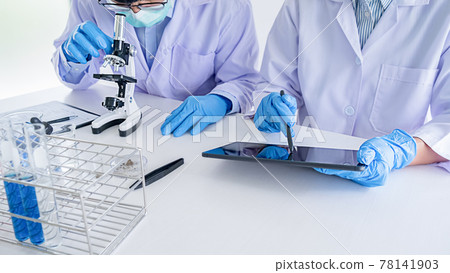 Medical or scientific researcher or man doctor looking at a test tube of clear solution in a laboratory 78141903