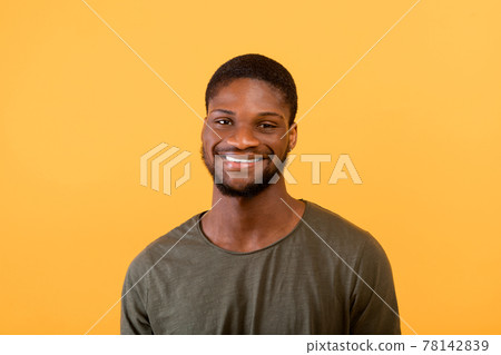 Male portrait. Positive african american man looking and smiling to camera isolated over yellow background Male portrait. Positive african american man looking and smiling to camera isolated over yellow background 78142839