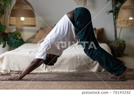 Young african man working out, standing in yoga downward facing dog pose, adho mukha svanasana 78143292