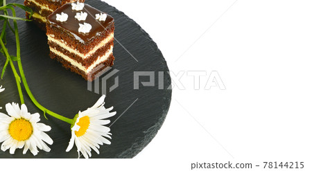 Chocolate cake and white daisies on a black tray isolated on a white. Free space for text. Wide photo. 78144215