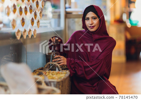 Arabian young muslim woman sitting in a cafe. Arabian young muslim woman sitting in a cafe. 78145470