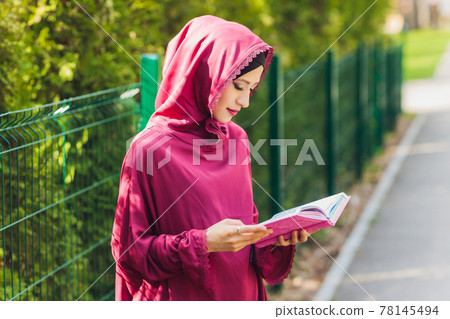 Confident Arab businessman smiling and walks of Dubai. Arab Business vumen hijab is in the streets against the skyscrapers of Dubai. The woman is dressed in a black abaya. 78145494