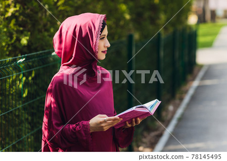 Confident Arab businessman smiling and walks of Dubai. Arab Business vumen hijab is in the streets against the skyscrapers of Dubai. The woman is dressed in a black abaya. 78145495