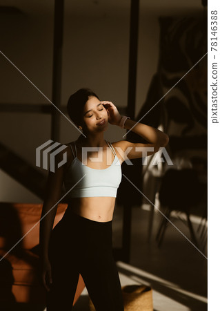 Relaxed young sportswoman dressed in activewear poses on camera. 78146388