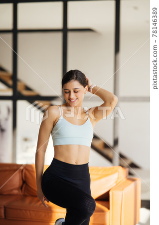 Relaxed young sportswoman dressed in activewear poses on camera. 78146389