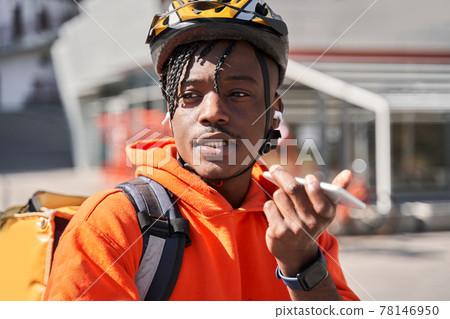 Delivery man wearing bicycle helmet and delivery backpack using smartphone Delivery man wearing bicycle helmet and delivery backpack using smartphone 78146950