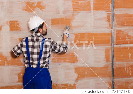 Workman is plastering the wall at the place 78147188