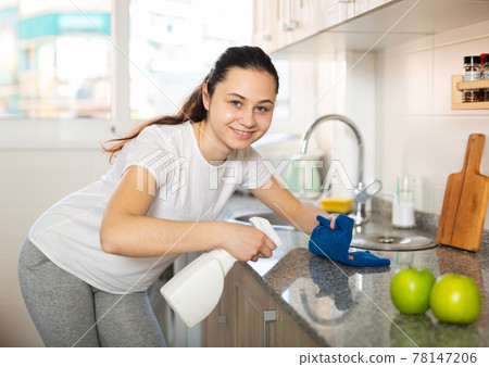 Friendly woman with rag cleaning kitchen at home 78147206