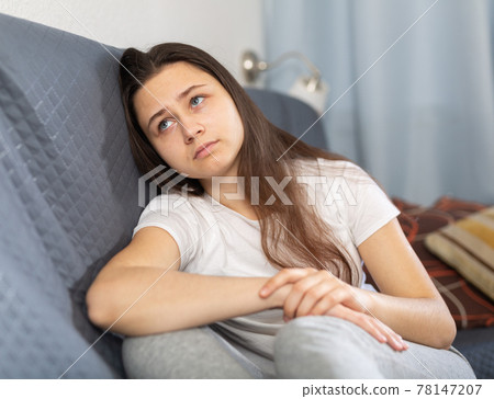 Depressed young woman sitting on sofa at home Depressed young woman sitting on sofa at home 78147207
