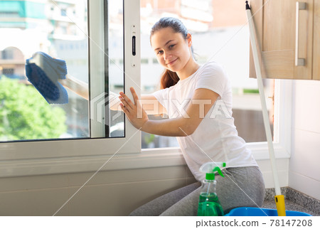 Portrait of young beautiful woman washing windows Portrait of young beautiful woman washing windows 78147208