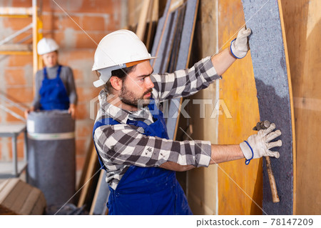 Two professional builders sheathe walls with insulation Two professional builders sheathe walls with insulation 78147209
