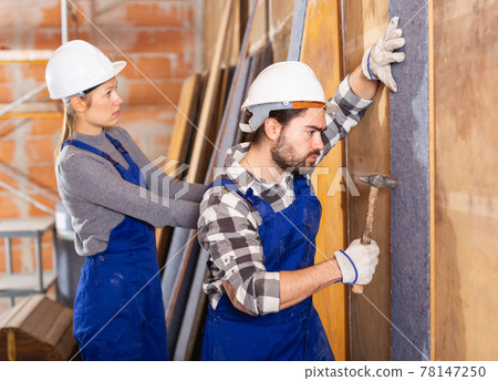 Two professional builders sheathe walls with insulation Two professional builders sheathe walls with insulation 78147250