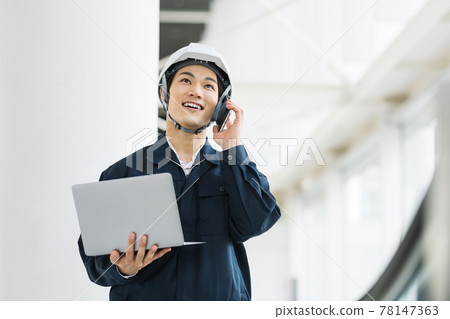 A man who is a construction management engineer talking on a smartphone 78147363