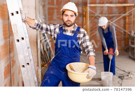 Portrait of builder in process of finishing work in cottage Portrait of builder in process of finishing work in cottage 78147396