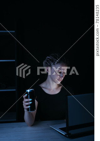 Focused woman drinking energy drink at night 78148235
