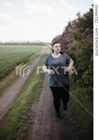 Overweight woman jogging outdoors at the open air 78148448