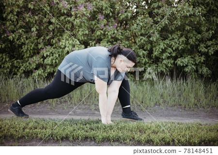Overweight woman warming up muscles before workout 78148451