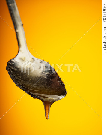 Metal spoon with natural honey on yellow Metal spoon with natural honey on yellow 78151950