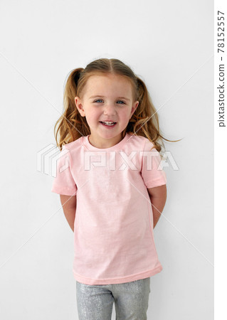 Happy little girl in pink shirt standing in studio Happy little girl in pink shirt standing in studio 78152557