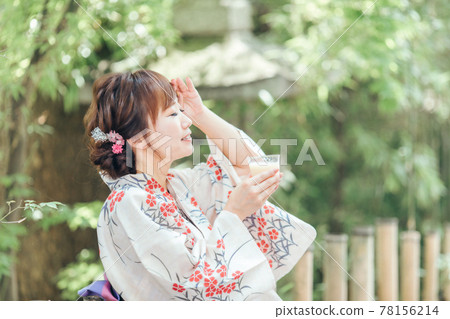 A woman in a yukata drinking a drink A woman in a yukata drinking a drink 78156214