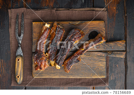 Grilled pork rib, on wooden serving board, with barbeque knife and meat fork, on old dark wooden table background, top view flat lay 78156689
