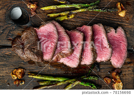 Sliced grilled marbled meat steak Filet Mignon, with onion and asparagus, on wooden serving board, top view flat lay 78156698