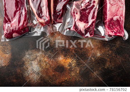 Beef steak vacuum, tomahawk, t bone, club steak, rib eye and tenderloin cuts, on old dark rustic background, top view flat lay, with copy space for text Beef steak vacuum, tomahawk, t bone, club steak, rib eye and tenderloin cuts, on old dark rustic background, top view flat lay, with copy space for text 78156702