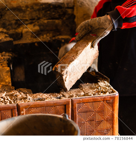Man destroys an old brick stove, black brick in soot, dismantling the old kitchen surface. Man destroys an old brick stove, black brick in soot, dismantling the old kitchen surface. 78156844