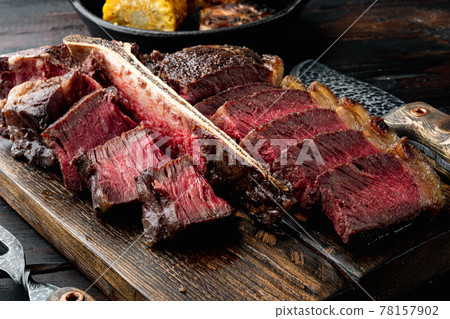 American cuisine. Sliced and roast T-bone or porterhouse beef medium rare meat Steak, on wooden serving board, on old dark wooden table background American cuisine. Sliced and roast T-bone or porterhouse beef medium rare meat Steak, on wooden serving board, on old dark wooden table background 78157902