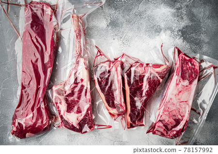 Plastic Market pack with fresh beef steak, tomahawk, t bone, club steak, rib eye and tenderloin cuts, on gray stone background, top view flat lay Plastic Market pack with fresh beef steak, tomahawk, t bone, club steak, rib eye and tenderloin cuts, on gray stone background, top view flat lay 78157992