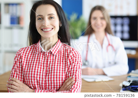 Smiling young woman patient on background of doctor in medical office Smiling young woman patient on background of doctor in medical office 78159136