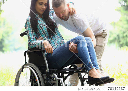 Man picks up disabled woman from wheelchair Man picks up disabled woman from wheelchair 78159287