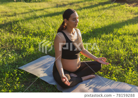 Young pregnant woman meditating in nature, practice yoga. Care of health and pregnancy Young pregnant woman meditating in nature, practice yoga. Care of health and pregnancy 78159288