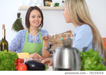 Two young happy woman making cooking in the kitchen. Friendship and culinary concept Two young happy woman making cooking in the kitchen. Friendship and culinary concept 78159358