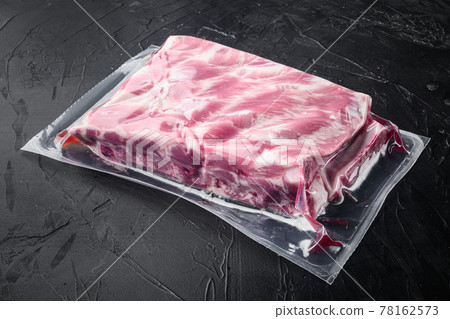 Vacuum packaging with raw pork rib, on black stone background, with copy space for text Vacuum packaging with raw pork rib, on black stone background, with copy space for text 78162573